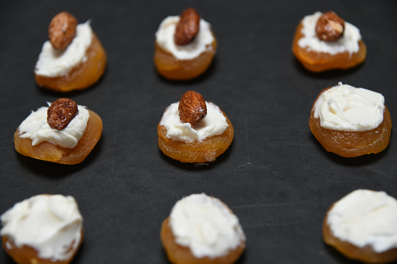 putting cheese and nuts on top of the apricots